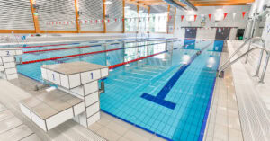 Schwimmbad mit modernen Startblöcken, klaren Wasserlinien, Sprungbrett und energetischer Atmosphäre, ideal für Wassersportarten, Aquafitness und Schwimmsporttraining.
