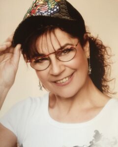 Fröhliche Frau mit Brille, Hut und Schmuck, die Spaß an Wassersport und Aqua Fit Kursen hat, um die Gesundheit und Fitness im Wasser zu verbessern.